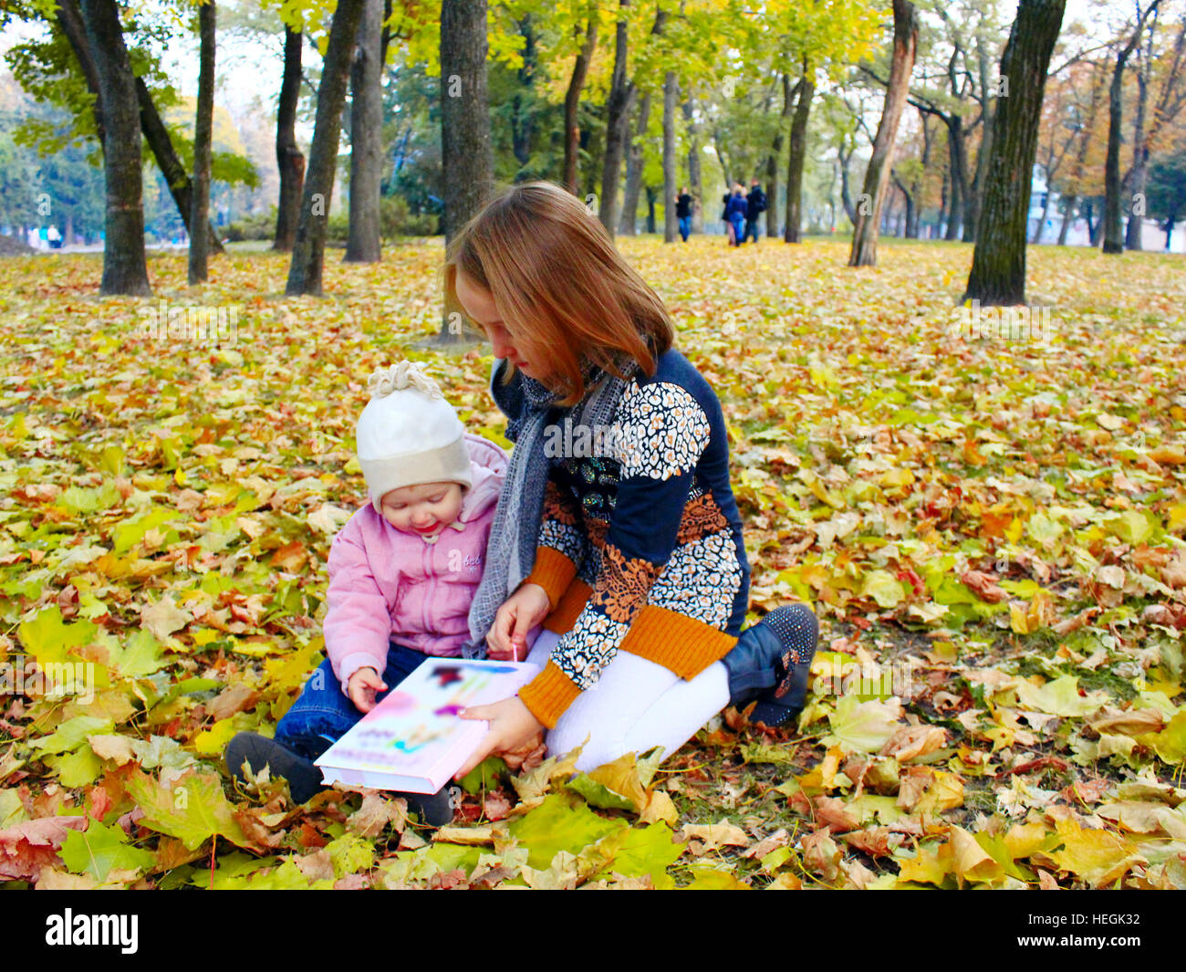 little girls sisters read the book in the autumn park Stock Photo