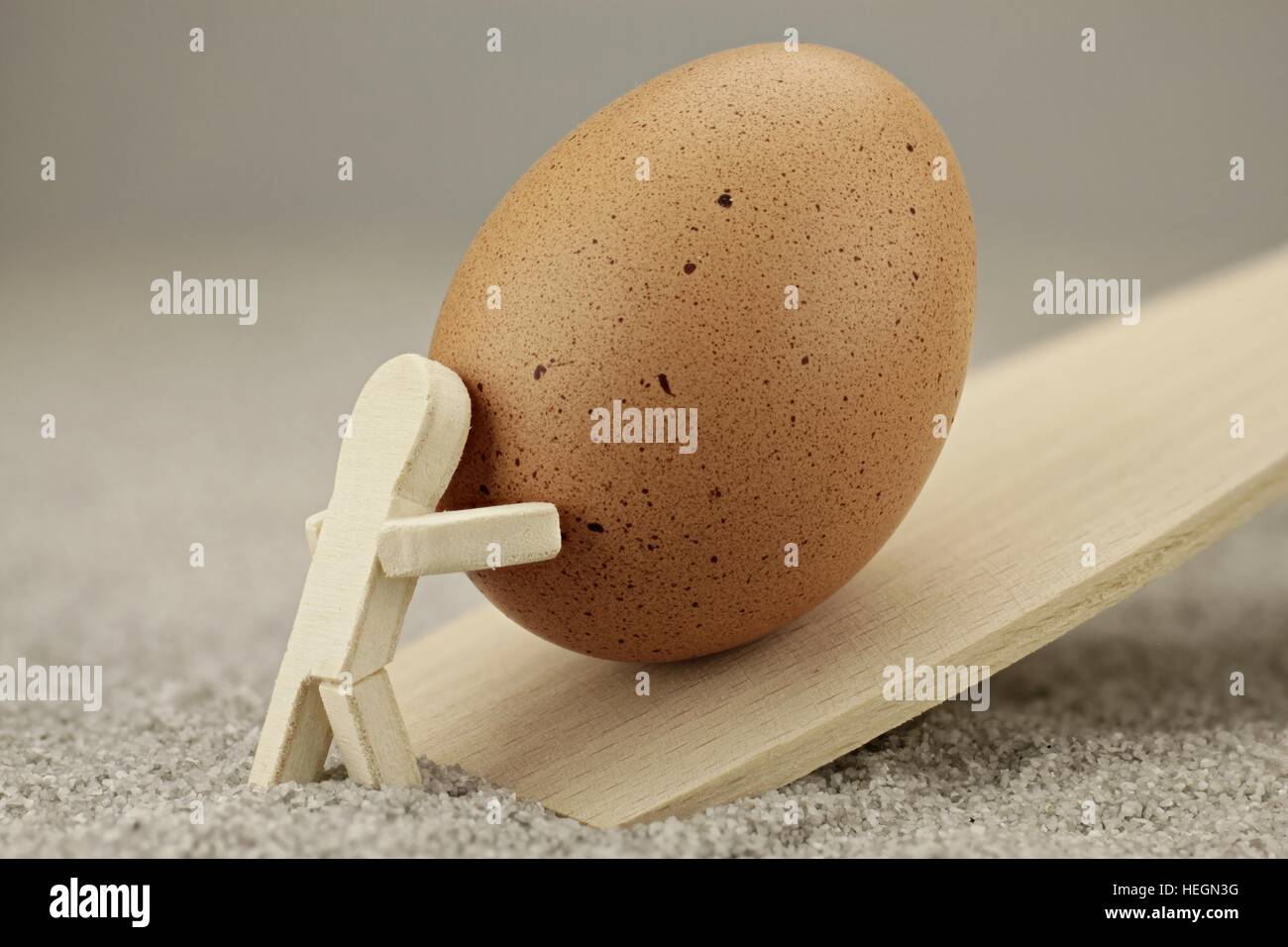 Small wooden man rolls up an egg Stock Photo