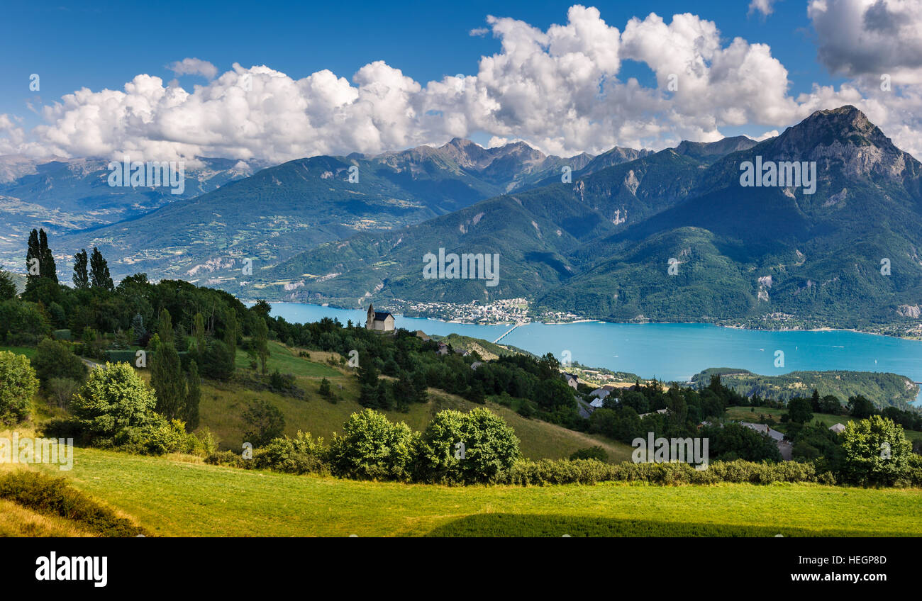 The village of Saint Apollinaire's church with Summer view on Savines-le-Lac, Serre Poncon Lake and Grand Morgon, Alps, France Stock Photo