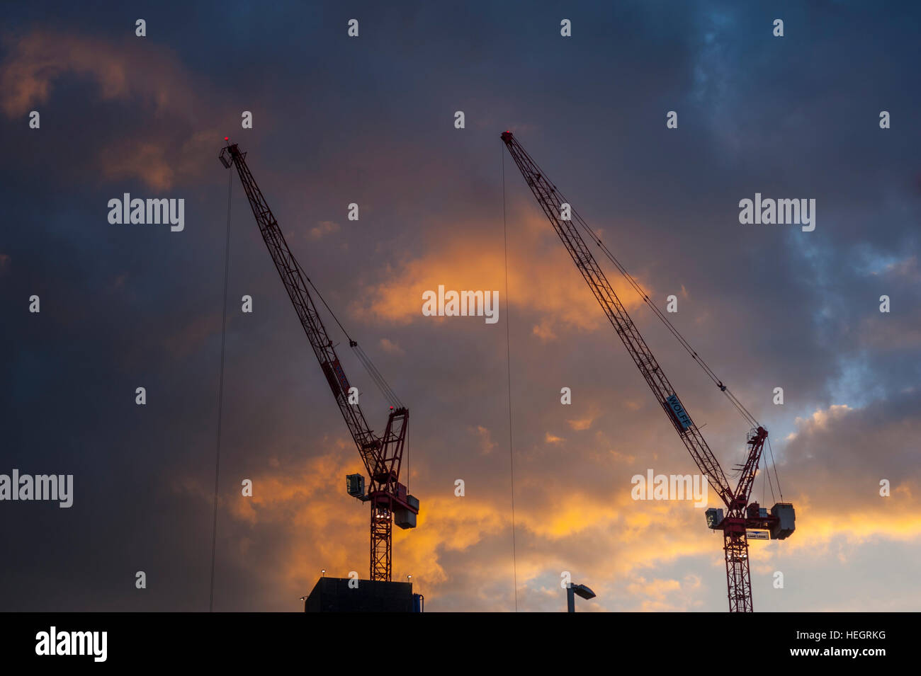 Lufting tower cranes against a sunset at Stratford East London. Stock Photo