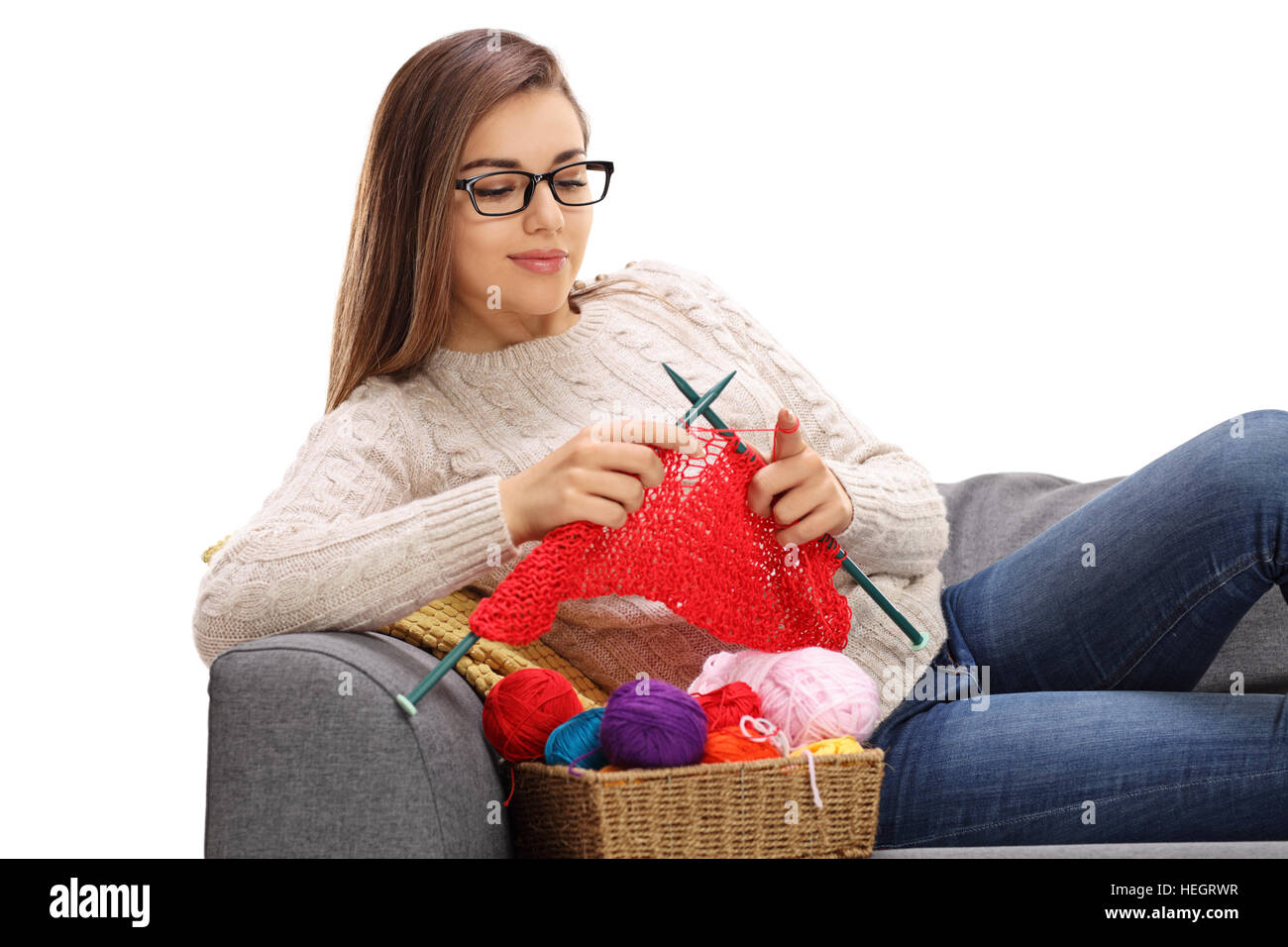 Joyful woman lying on a sofa and knitting isolated on white background ...