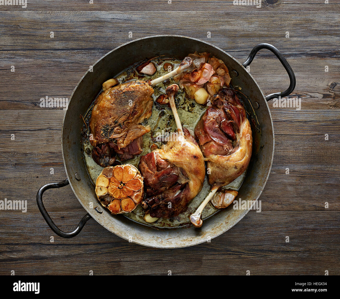 pan roasted duck legs garlic rustic tabletop overhead Stock Photo