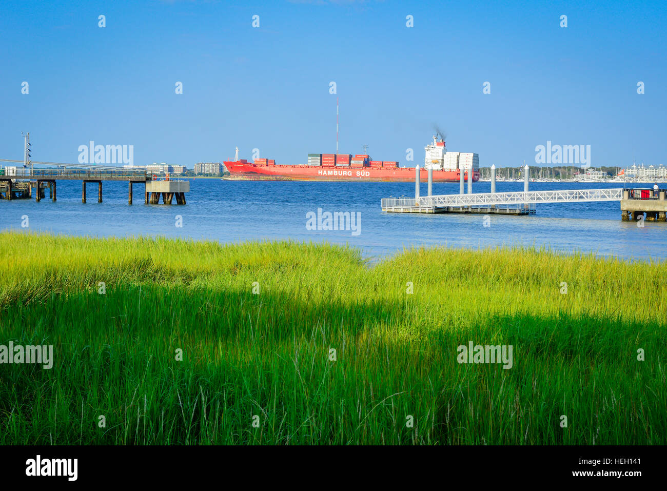 Lowcountry Green Grassy marsh along the wharves & docks on Cooper River with huge container ships in distance in Charleston SC Stock Photo