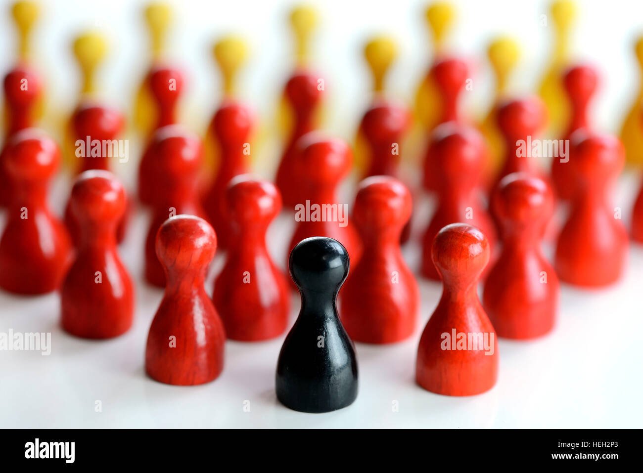 Schwarze Spielfigur vor vielen roten und gelben Figuren, Symbolfoto fuer Populismus in Deutschland Stock Photo