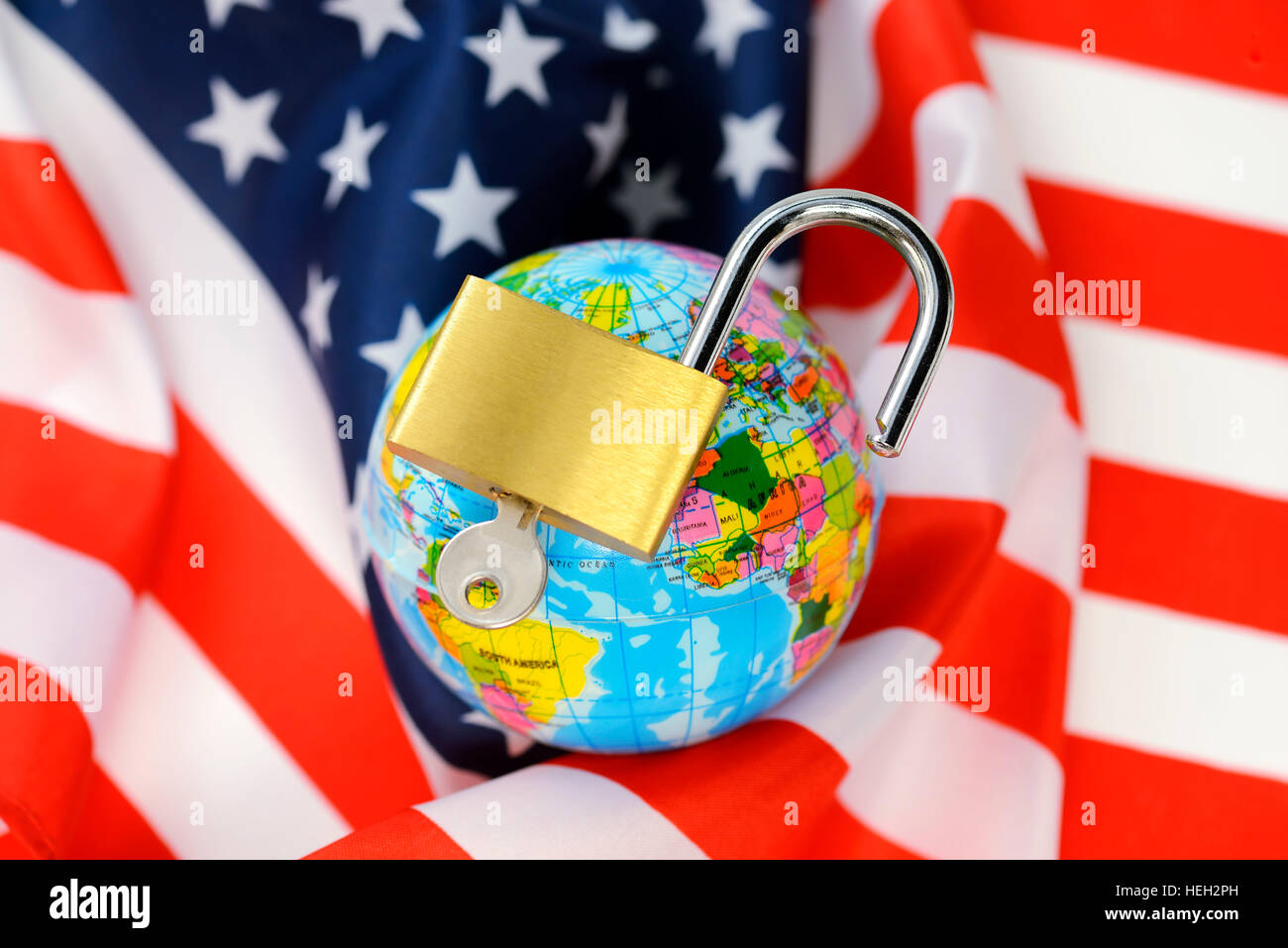 Weltkugel mit einem offenen Vorhaengeschloss auf einer USA-Fahne, amerikanische Sicherheitspolitik im Wandel Stock Photo