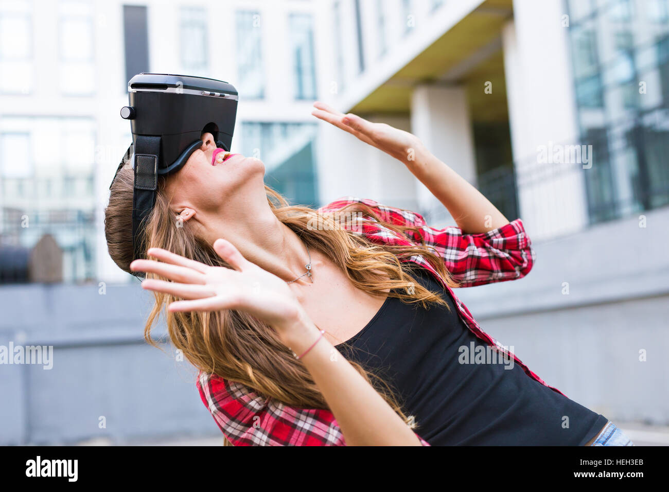 Beautiful young woman wearing virtual reality headset in an urban ...