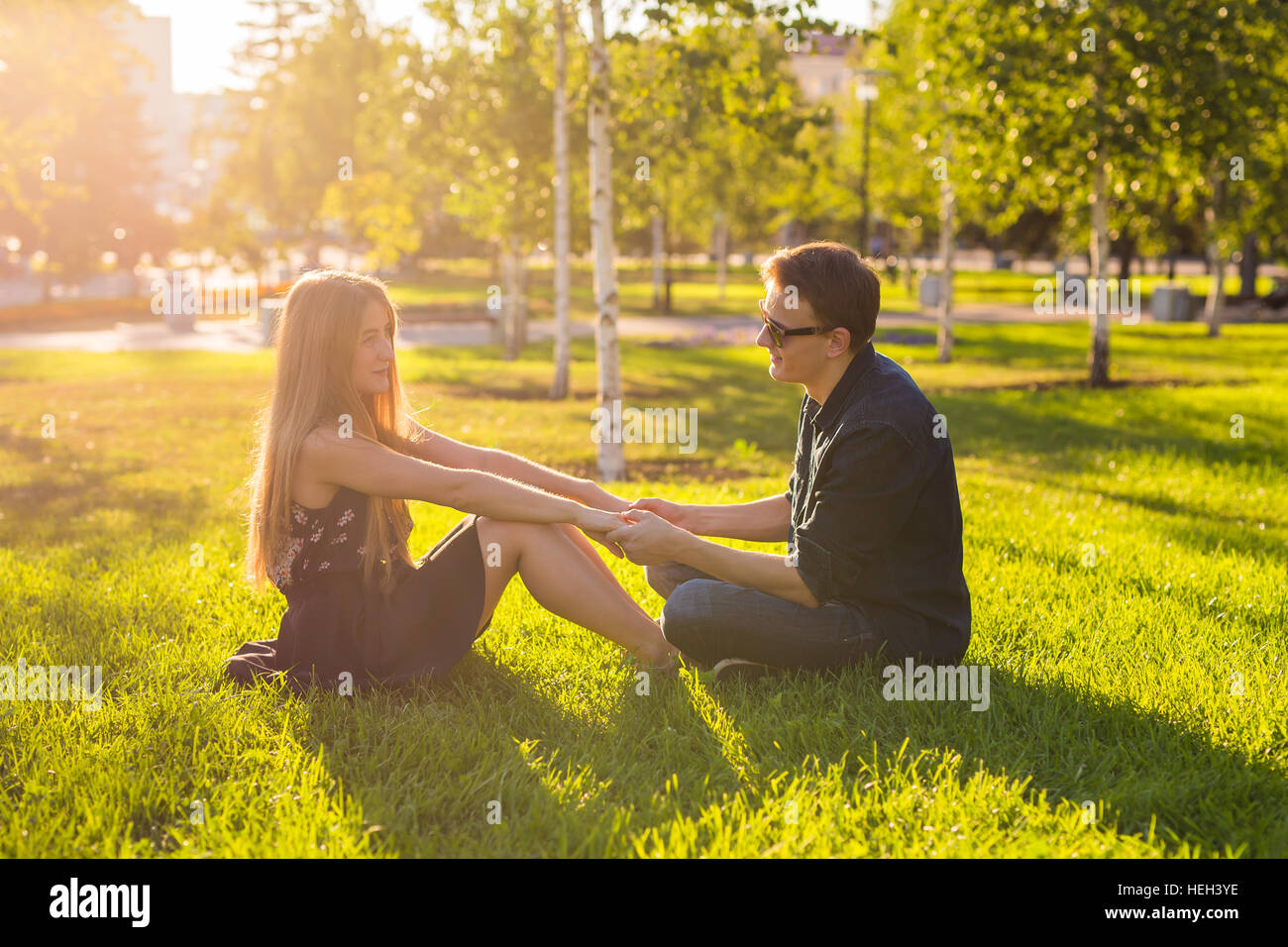 couple in the park sitting on the grass, have a good time together ...