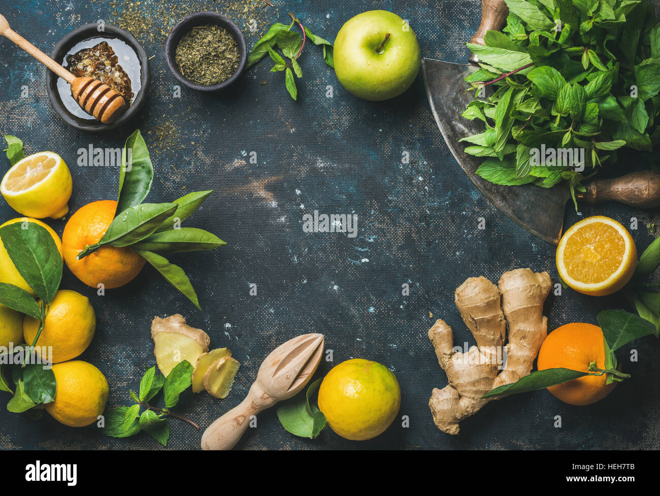 Ingredients for making natural hot drink. Oranges, fresh mint, lemons, ginger, honey, apple and spices in bowl over plywood background, top view, copy Stock Photo