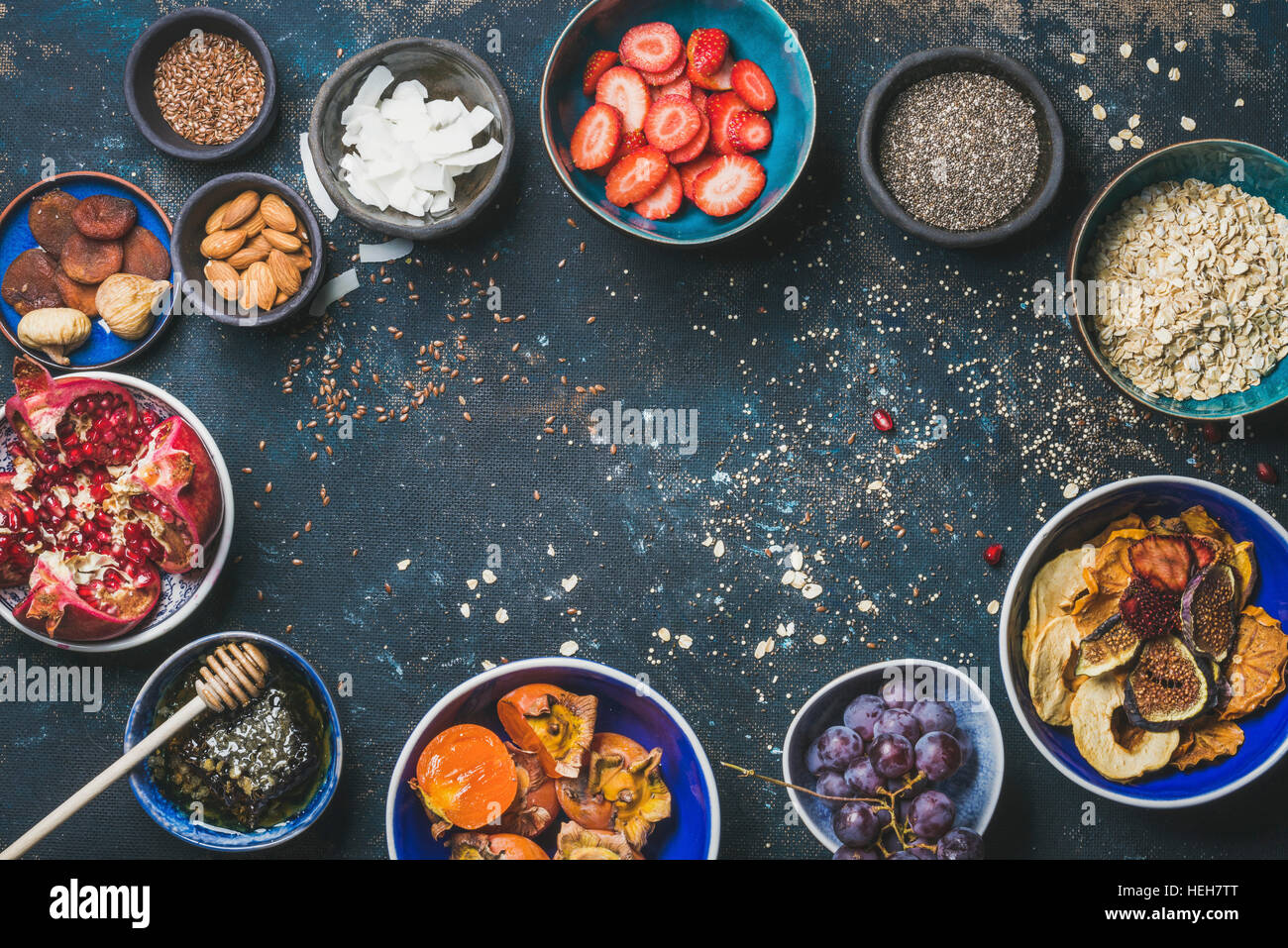 Ingredients for healthy breakfast over dark blue background, top view, copy space. Fresh and dried fruit, chia seeds, oatmeal, almonds, honey. Clean e Stock Photo