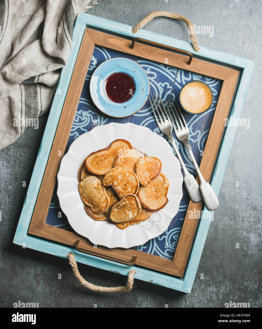 Breakfast tray with whole grain pancakes, raspberry jam and coffee espresso. Top view, shabby dark blue background Stock Photo