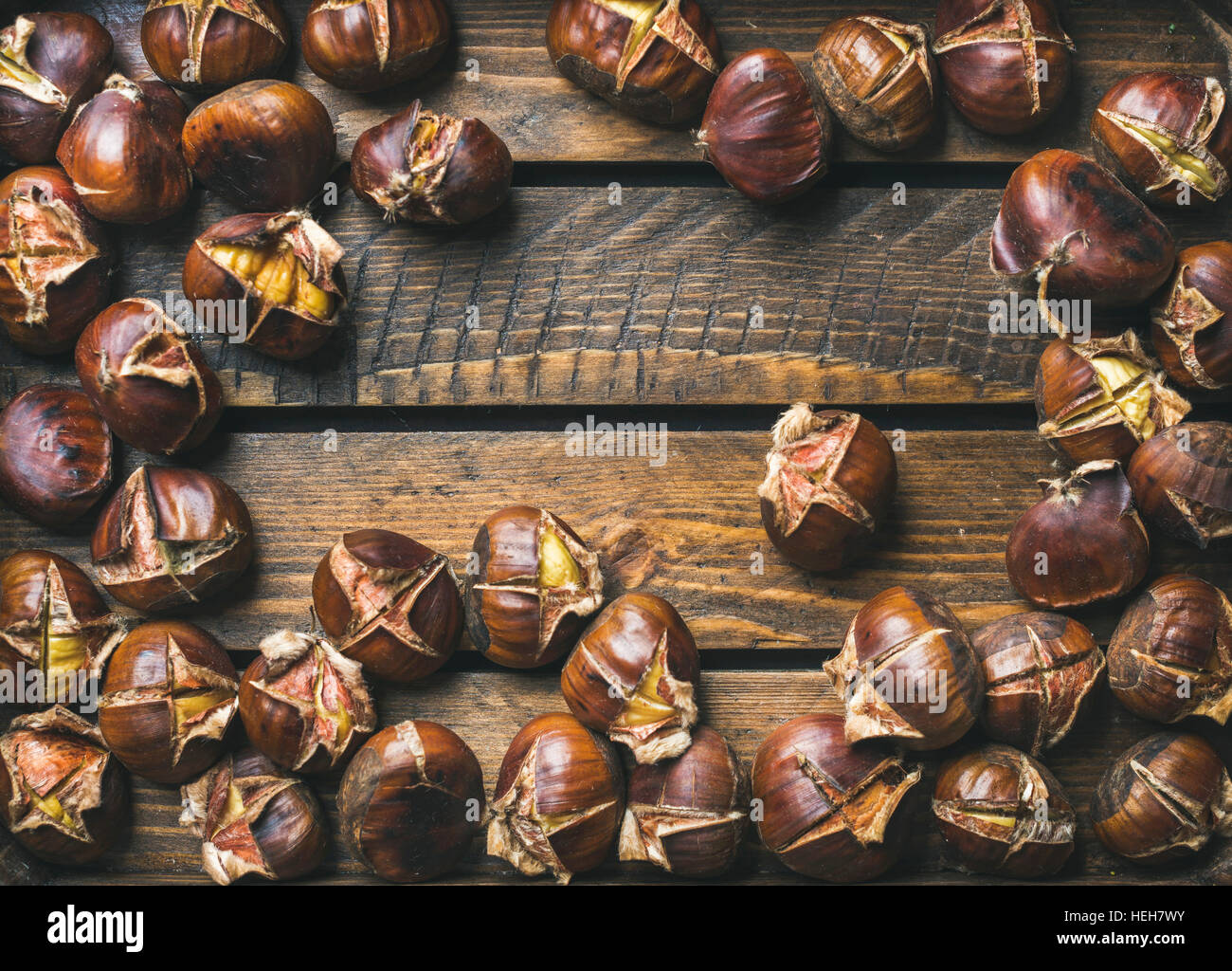 Close-up of roasted chestnuts over rustic wooden table background, top view, copy space, horizontal composition Stock Photo