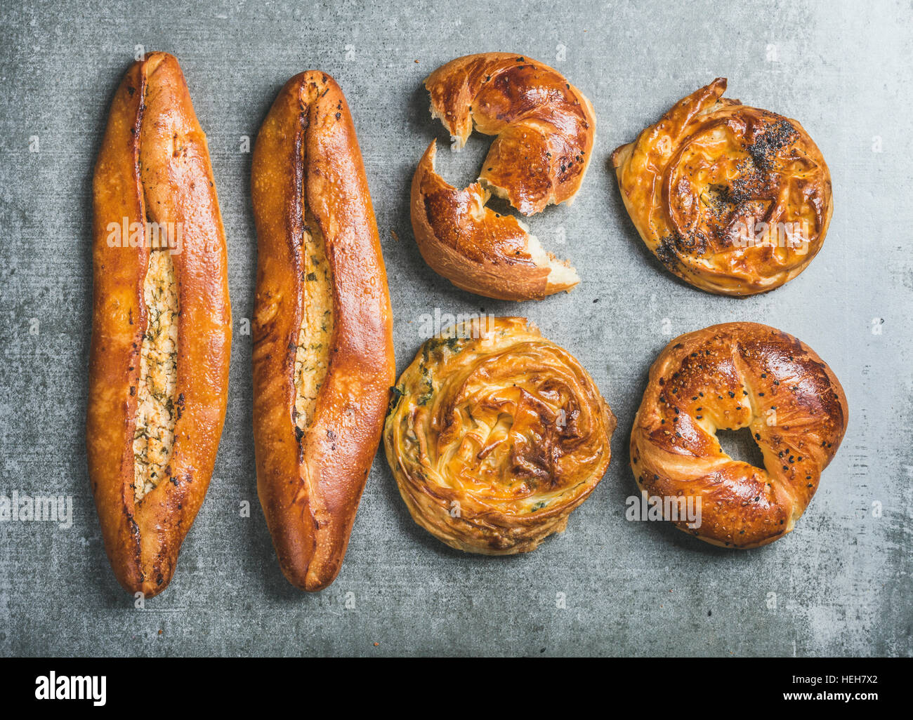 Oriental style Turkish pastry with different fillings over grey stone background, top view. Bagels with black sesame, borek with spinach and poppy see Stock Photo