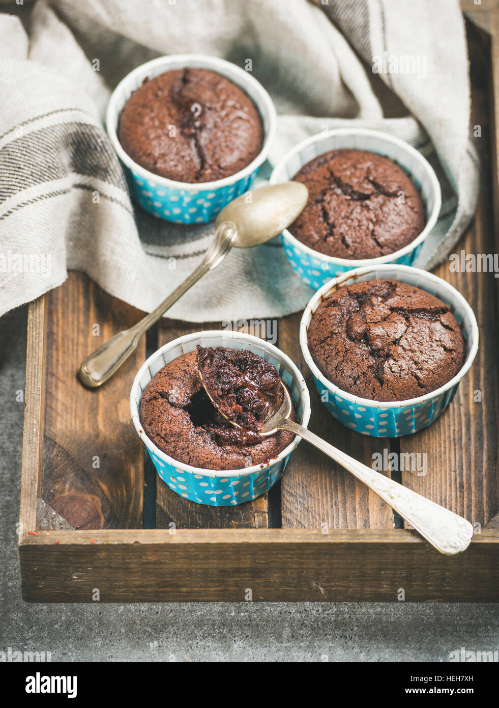 Chocolate souffle in blue individual baking cups in wooden serving tray over grey concrete background, selective focus Stock Photo