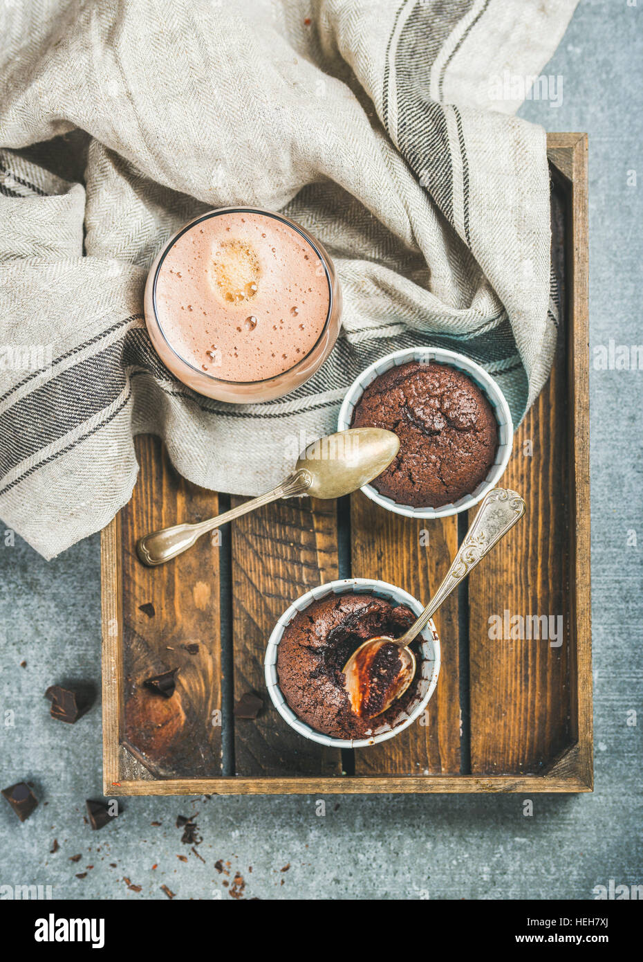 Chocolate souffle in blue individual baking cups and chocolate mocha coffee in wooden serving tray over grey concrete background, top view Stock Photo
