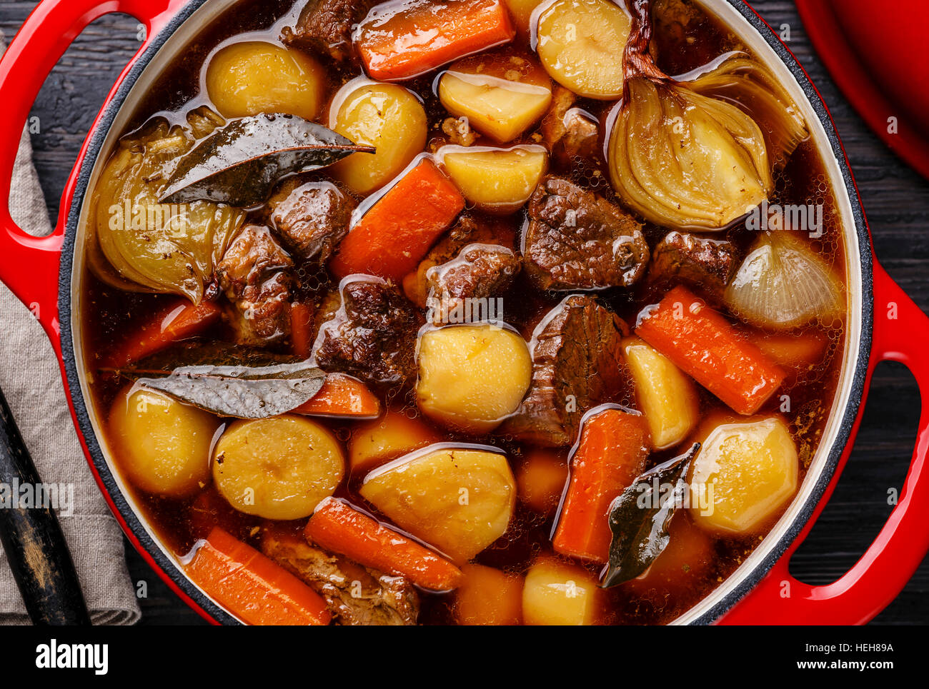 Beef meat stewed with potatoes, carrots and spices in cast iron pot close up Stock Photo