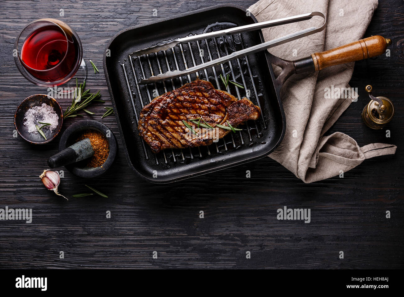 Grilled Steak Striploin on pan and red wine on black burned wooden background copy space Stock Photo