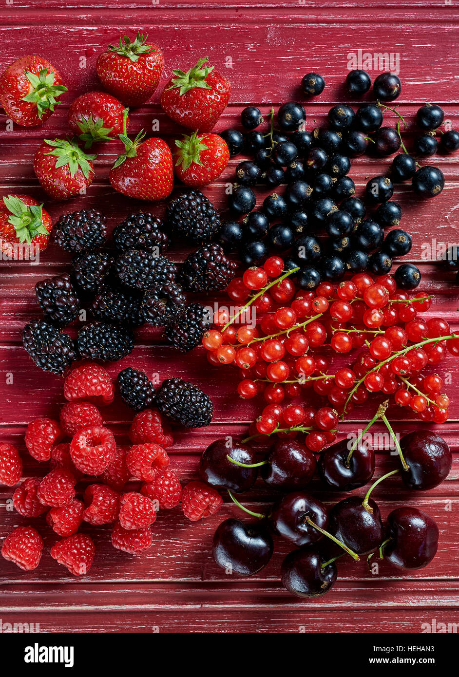 Red fruits strawberries black berries red currants cherries black currants red raspberries over head group shiny vibrant vivid fresh healthy sweet Stock Photo