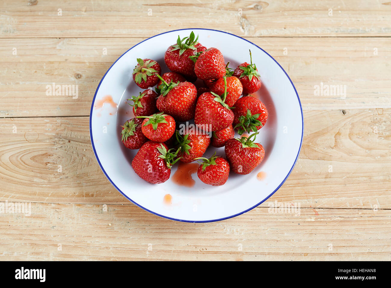 strawberries fruit red portion stalks fresh picked white skin pale wooden table top abundant offering giving Strawberry white enamel plate Fragaria Stock Photo