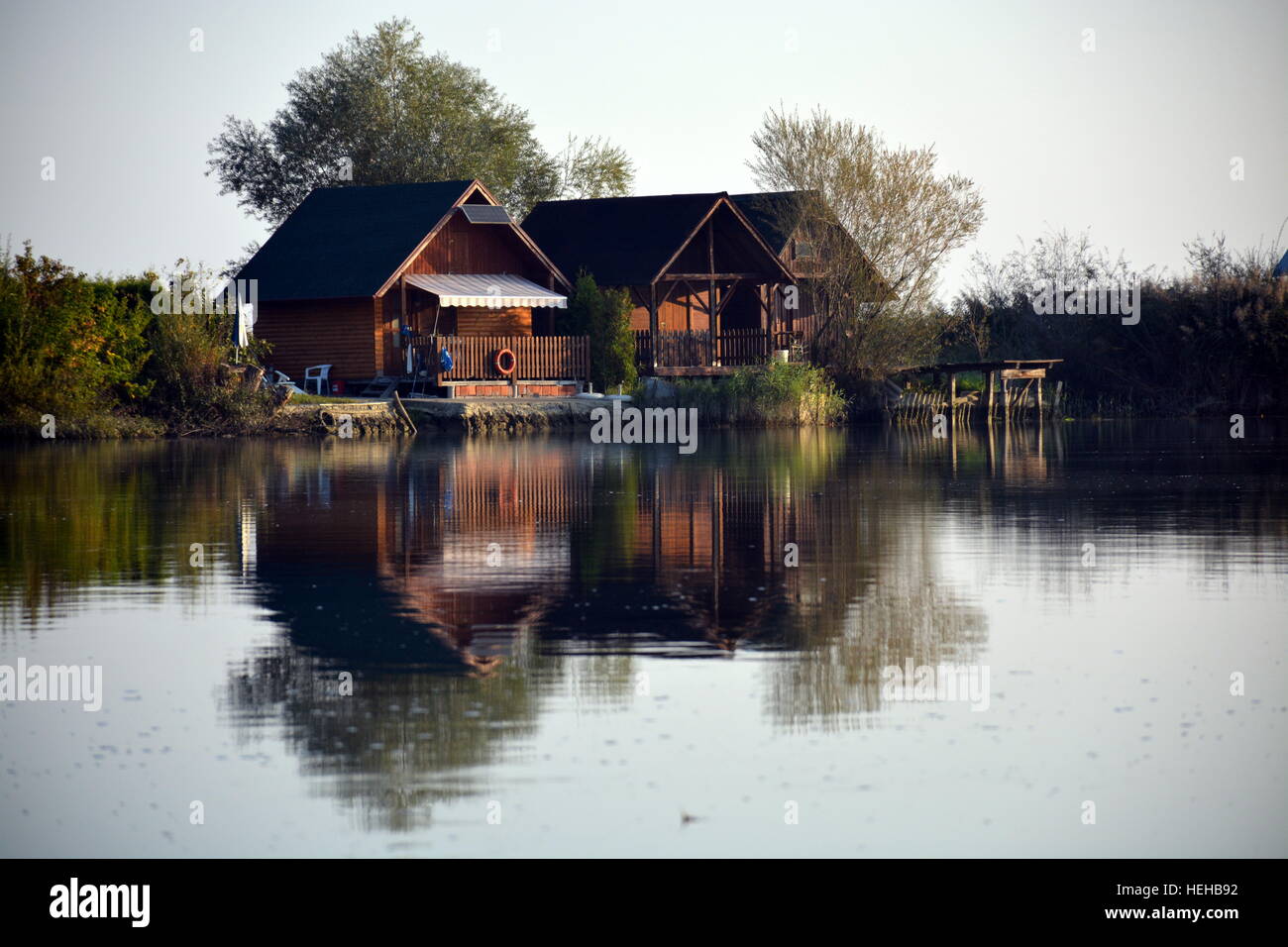 River houses mirroring in the Drava river. River stillness makes beautiful reflections. Stock Photo
