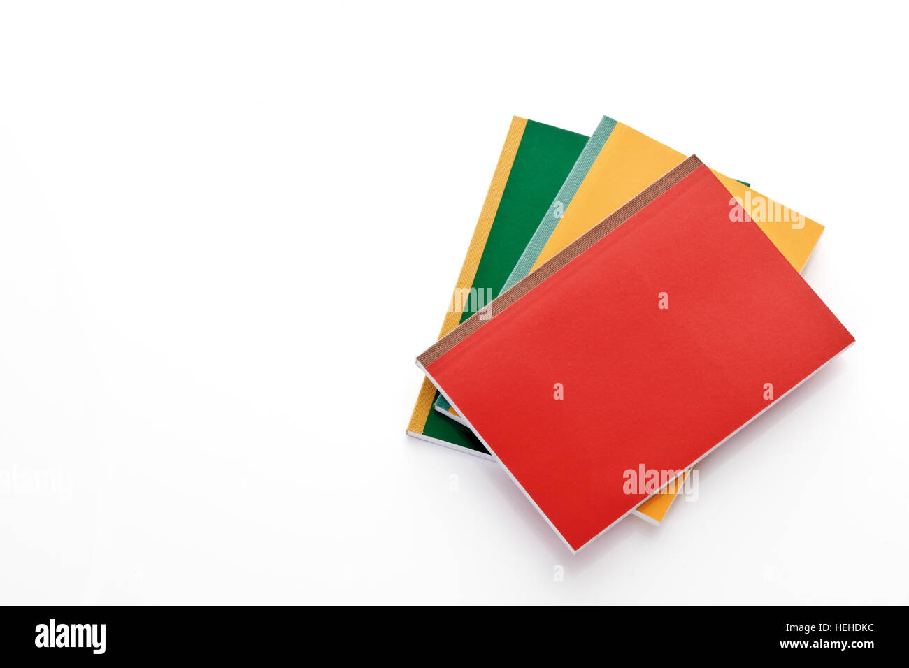 Three school notebooks in green, yellow and red Stock Photo - Alamy