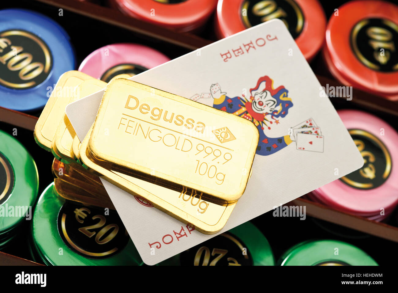 Gold bars on a roulette table with casino chips and a joker card Stock