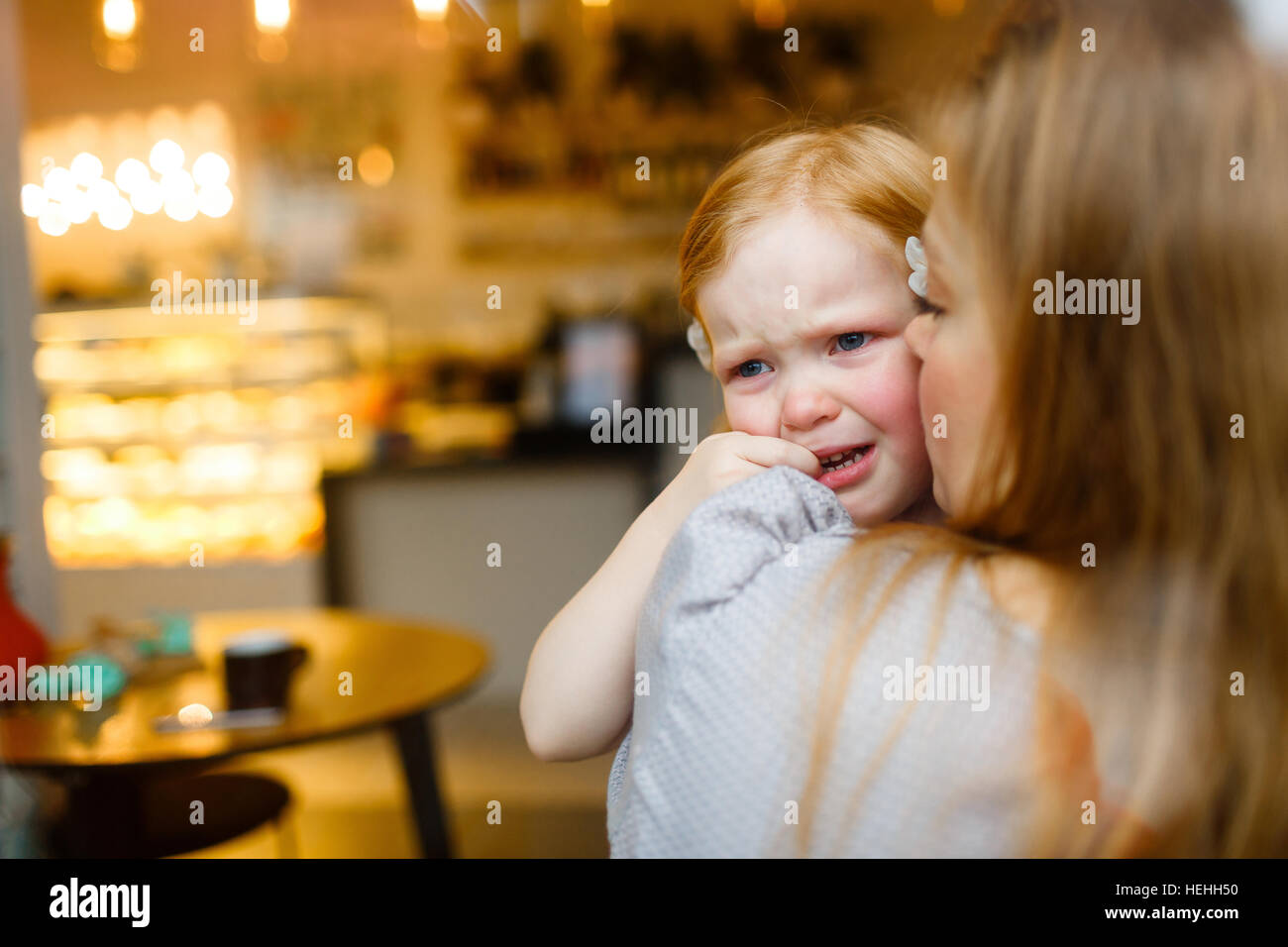 Mother kissing crying child while comforting her Stock Photo