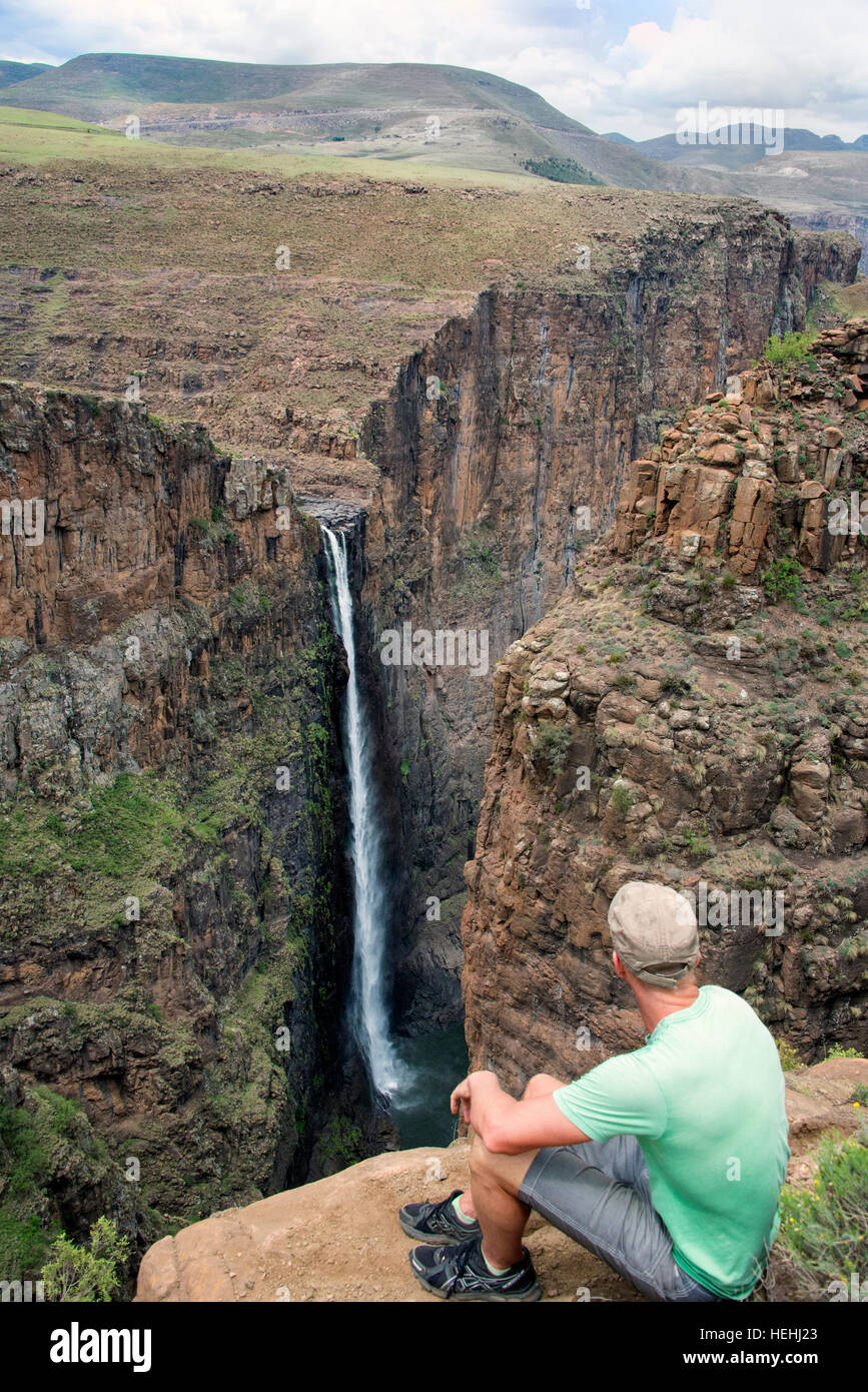 Man looking across a deep red rock canyon at Semonkong waterfall, Lesotho Southern Africa Stock Photo