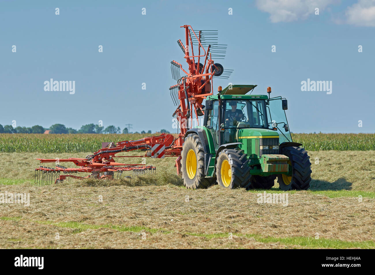 A John Deere 6610 tractor with a Kuhn rotary rake using one rotor for making small windrows for quicker drying of the hay. Stock Photo