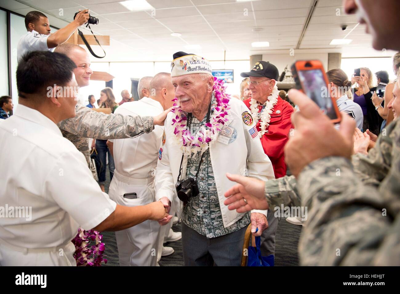 A World War II Pearl Harbor U.S. veteran is greeted by U.S. soldiers with floral leis after arriving at the Honolulu International Airport to participate in commemoration events to honoring the 75th anniversary of the Pearl Harbor attacks December 3, 2016 in Honolulu, Hawaii. Stock Photo