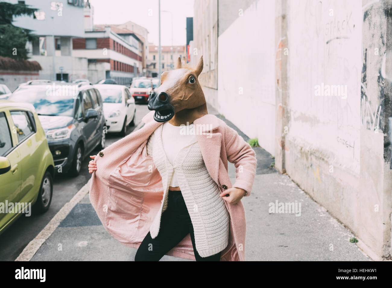 Woman wearing horse mask dancing outdoor in the city strange, absurd