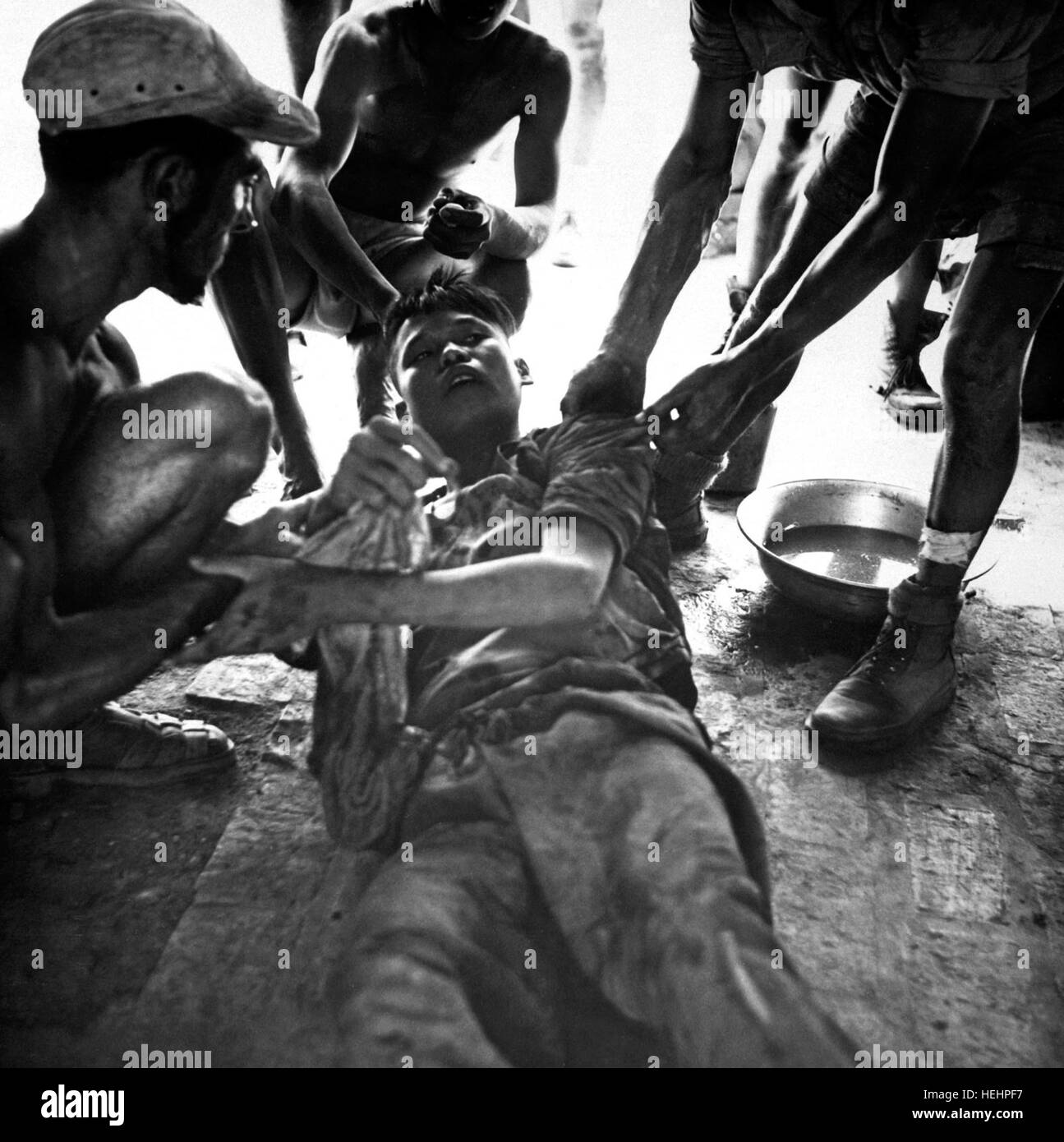 A wounded Vietminh prisoner is given first aid by Franco Vietnamese medicals after hot fire fight near Hung Yen, south of Hanoi.  Ca.  1954  (USIA) EXACT DATE SHOT UNKNOWN NARA FILE #:  306-PS-54-11793 WAR & CONFLICT BOOK #:  384 HD-SN-99-02043 Stock Photo