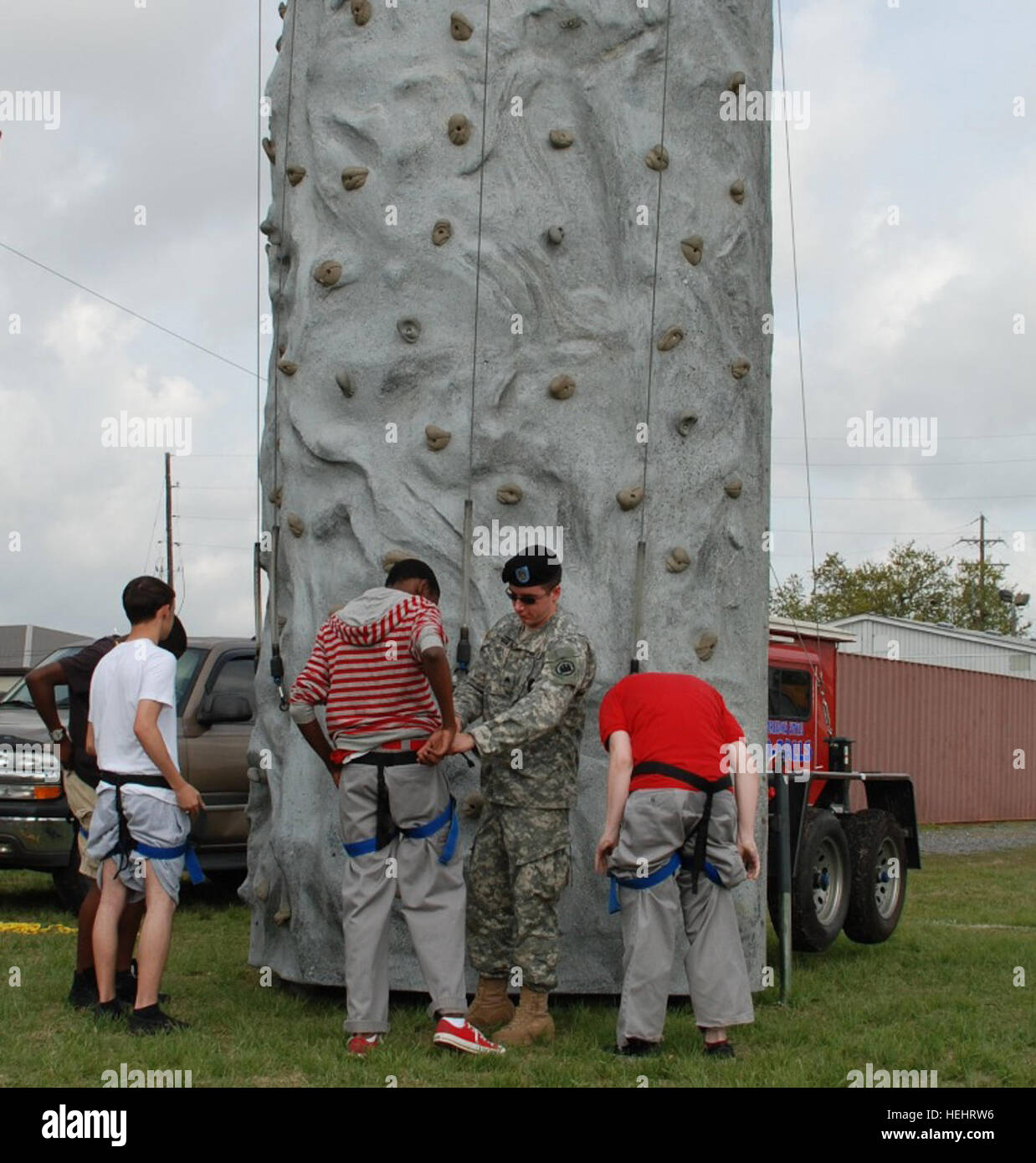 Louisiana Army National Guardsmen Sgt. Lex B. Putnam of New Orleans, helps cadets of the West Jefferson High School Air Force Junior Reserve Officers Training Corps team gear up before climbing a rock wall during a Military Day picnic in Harvey, La., March 13. The students were given the opportunity to interact with Soldiers, while receiving hands-on experience with equipment, which included a howitzer, a boat display and a Blackhawk helicopter. National Guard rewards local JROTC cadets with fun, relaxation 159374 Stock Photo
