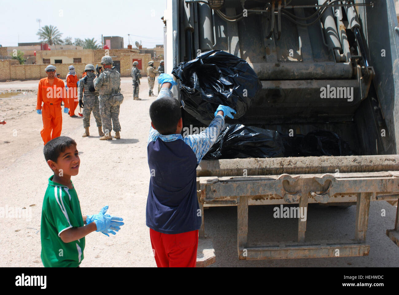 A local boy throws a trash bag into the back of a garbage truck during Dujaylah Pride Day April 18. Kids joined in the event that showed the local community the unity between the Iraqi security forces, Government of Iraq and coalition forces to strengthen community ties. Iraqi security forces lead the way for Dujaylah Pride Day 166217 Stock Photo