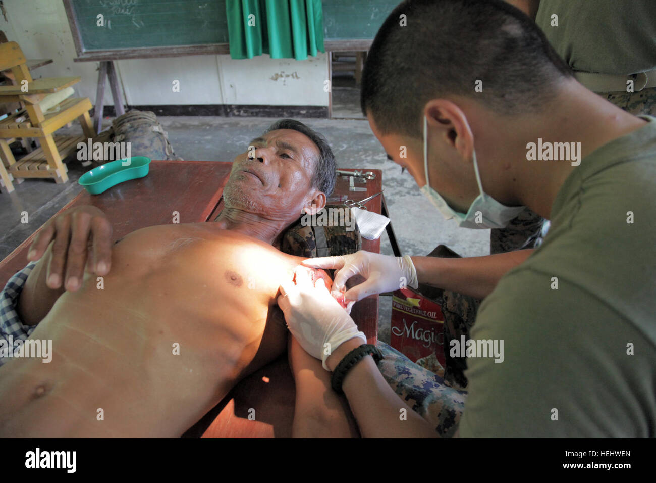 Petty Officer 3rd Class Justin Azucenas, a hospital corpsman assigned to Health Service Support Platoon, Combat Logistics Battalion 31, 31st Marine Expeditionary Unit, stitches the wound of a local man at Umiray Elementary School during a medical civic action project supporting Balikatan 2009. Civil military humanitarian assistance activities enable Armed Forces of the Philippines and U.S. personnel to get to know each other, train together, and provide assistance in communities where the need is greatest, improving their ability to operate as one team on joint projects. Balikatan 2009 167373 Stock Photo