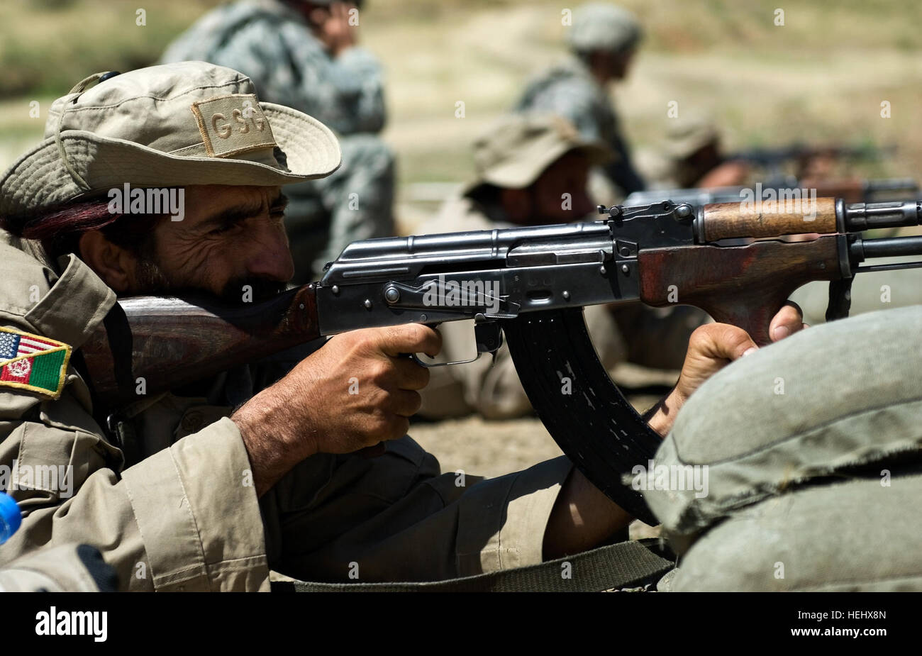 An Afghan security guard, assigned to Forward Operating Base Torkham, fires an AK-47 assault rifle while an American Soldier coaches him on proper shooting techniques during a weapons range hosted by the 527th Military Police Company, at FOB Torkham, in Afghanistan's Nangarhar province, May 12. U.S. hosts weapons range for Afghan Security Guards 171763 Stock Photo
