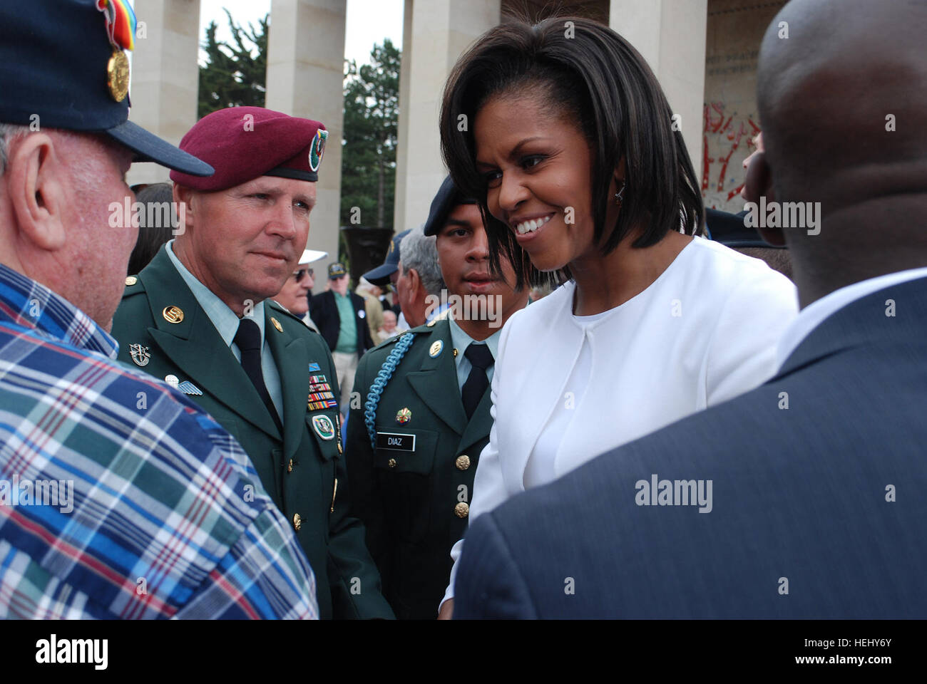 COLLEVILLE-SUR-MER, FRANCE – First Lady Michelle Obama greets a Second World War veteran while Sgt. Major Brian Card looks on at the 65th D-Day Anniversary ceremonies here on Jun 6. Card, an Army Reserve Soldier, was escorting veterans at the event. He is assigned to the U.S. Army Civil Affairs and Psychological Operations Command (Airborne), located At Fort Bragg, North Carolina. Band of brothers 177855 Stock Photo