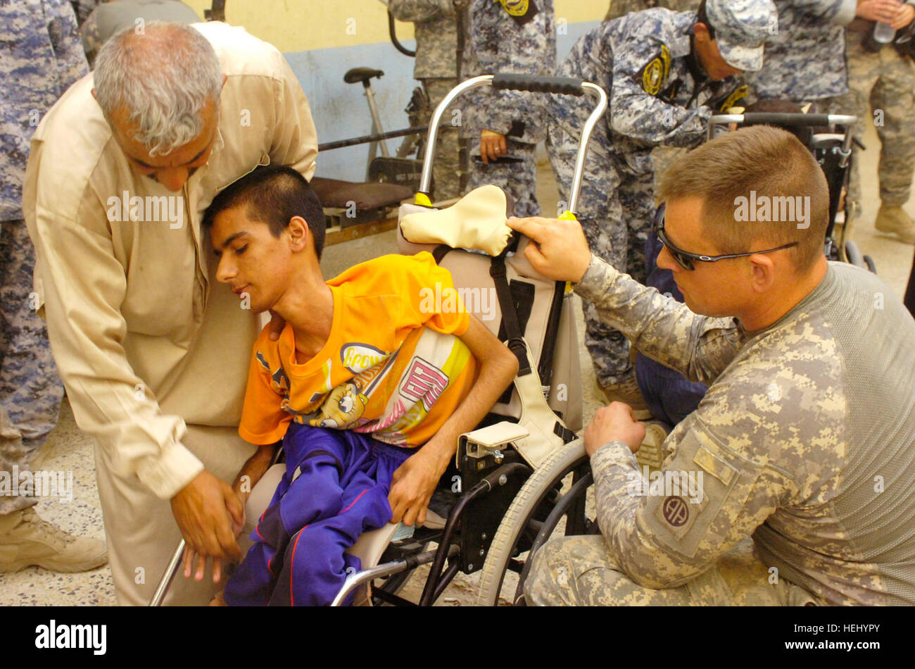 Spc. William Edwards, of Mansfield, Mass., helps an Iraqi man place his handicapped son in a new