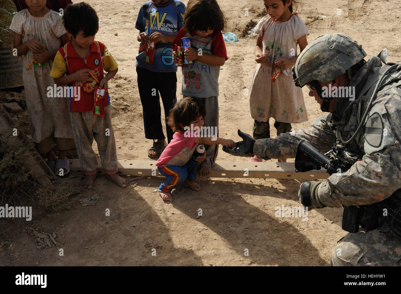 U.S. Army Staff Sgt. Matthew Rudy of Lancaster, Penn., with 2nd Battalion, 5th Cavalry Regiment, 1st Brigade Combat Team, 1st Cavalry Division,gives candy and school supplies to Iraqi children. Soldiers from 2-5 Cav. provided security while Iraqi soldiers searched the area surrounding Joint Security Station Ur, June 22. U.S. Soldiers Secure Area while Iraqi Soldiers Search 183361 Stock Photo