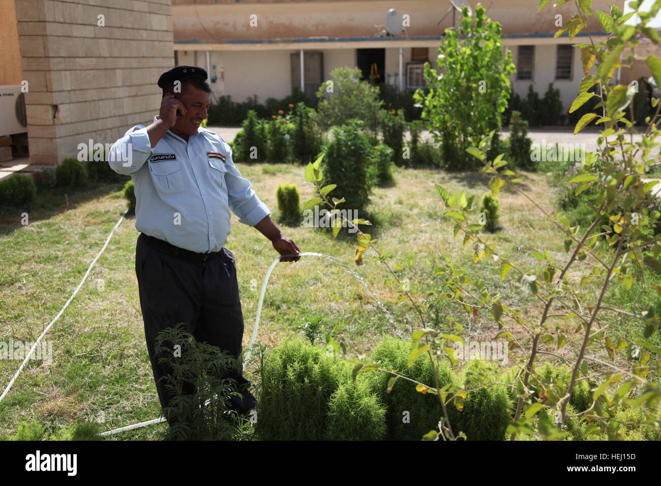 An Iraqi policeman waters the plants at the Altun Kapri police station at Altun Kapri, Iraq, July 30. Citizens of Altun Kapri 193563 Stock Photo