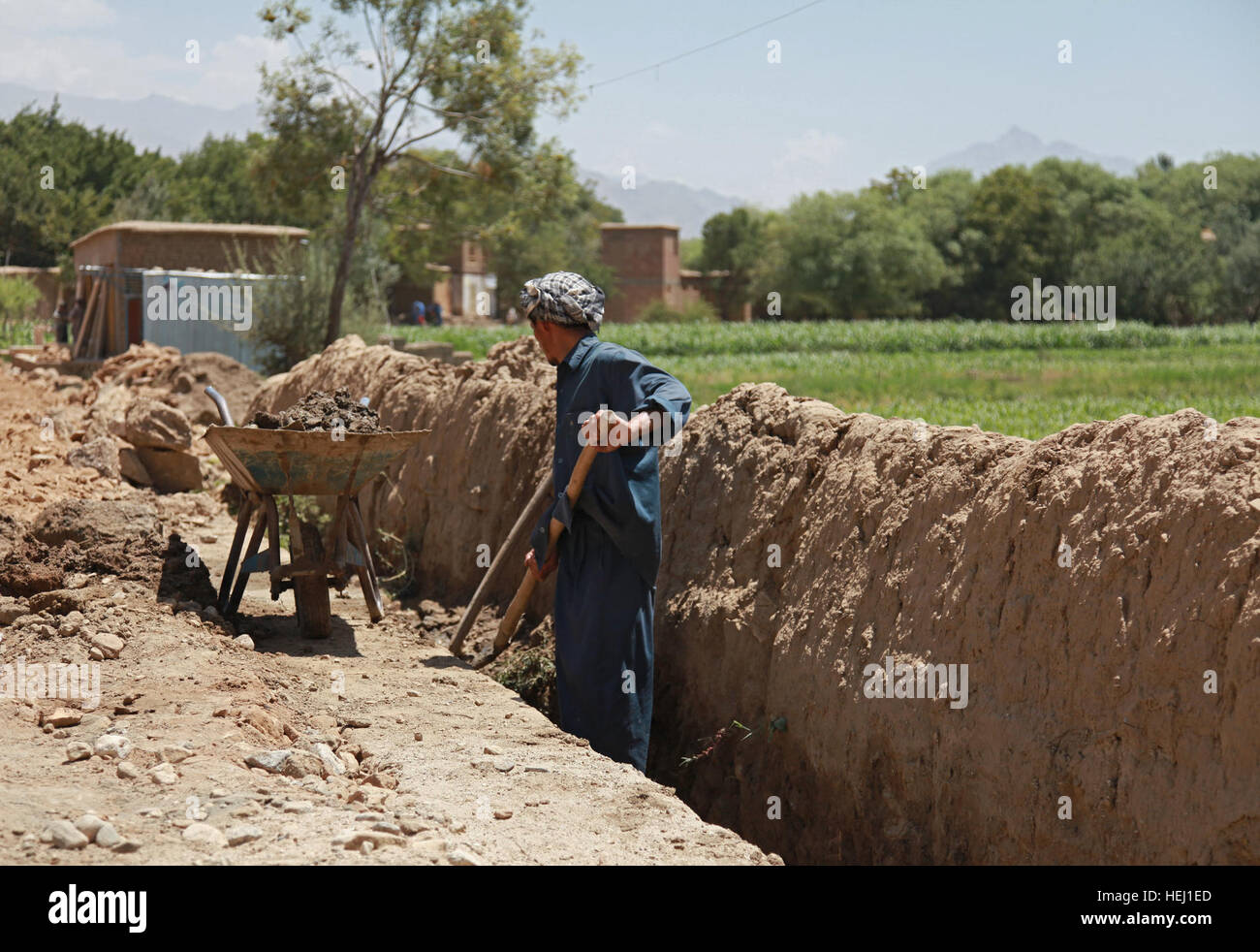 An Afghan construction worker digs a water canal on the side of a road