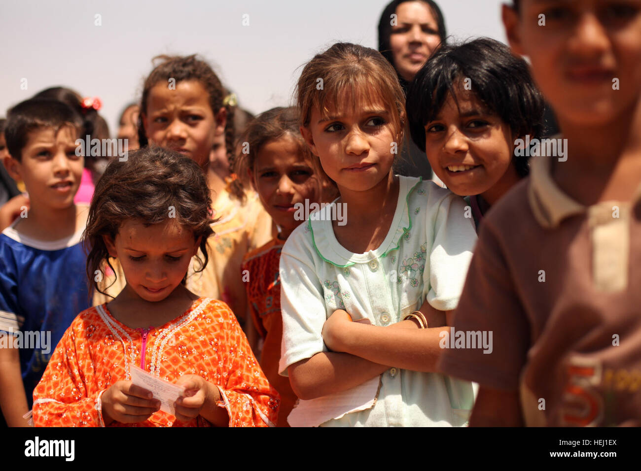 Local children wait patiently for their names to be called during a humanitarian-aid mission, supported by U.S. Soldiers assigned to Golf Battery, 82nd Field Artillery Regiment, 3rd Battalion, 2nd Brigade Combat Team, 1st Cavalry Division, in Adalla, Iraq, Aug. 9. Cavalrymen, Iraqi police go on humanitarian mission 193858 Stock Photo