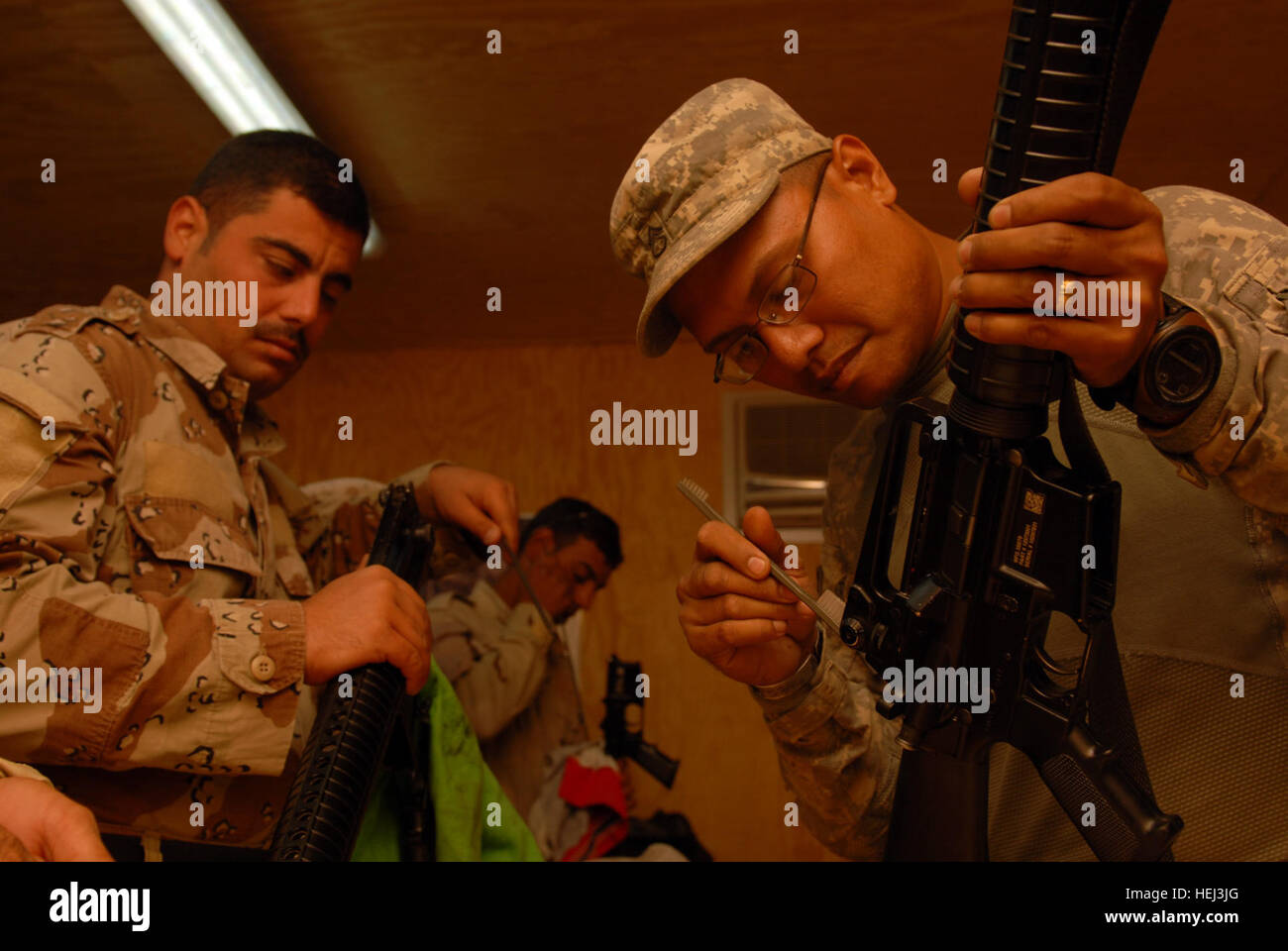 Staff Sgt. Benito Santos (right) shows an Iraqi soldier how to clean his weapon using a small brush at the Warrior Academy at Joint Security Station Ur, Sept. 16. Santos, an infantry platoon sergeant assigned to Company A, 2nd Battalion, 5th Cavalry Regiment, 1st Brigade Combat Team, 1st Cavalry Division, is one of the instructors of the academy. 'We make it so that when they come here, they enjoy it,' said Santos, a native of Kagman-3, Saipan. 'We make it so they tell their other buddies and they want to come here.' Warrior Academy helps Iraqis improve battle skills 205079 Stock Photo