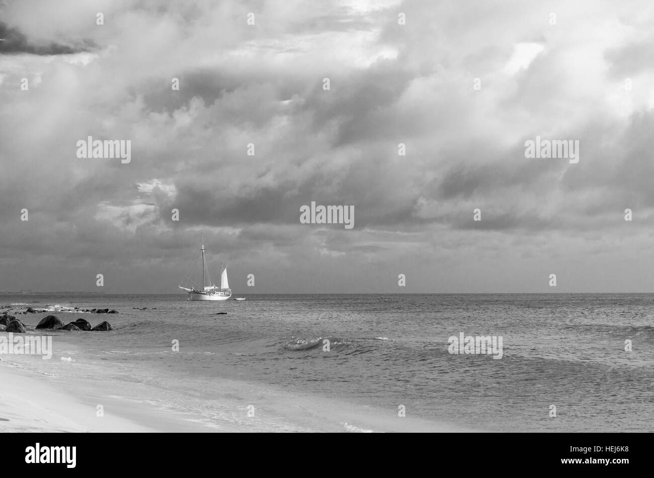 Picture showing a big sailboat on sea navigating towards the beach. The image was taken from Arashi Beach, Aruba, in the Caribbean Sea. Stock Photo