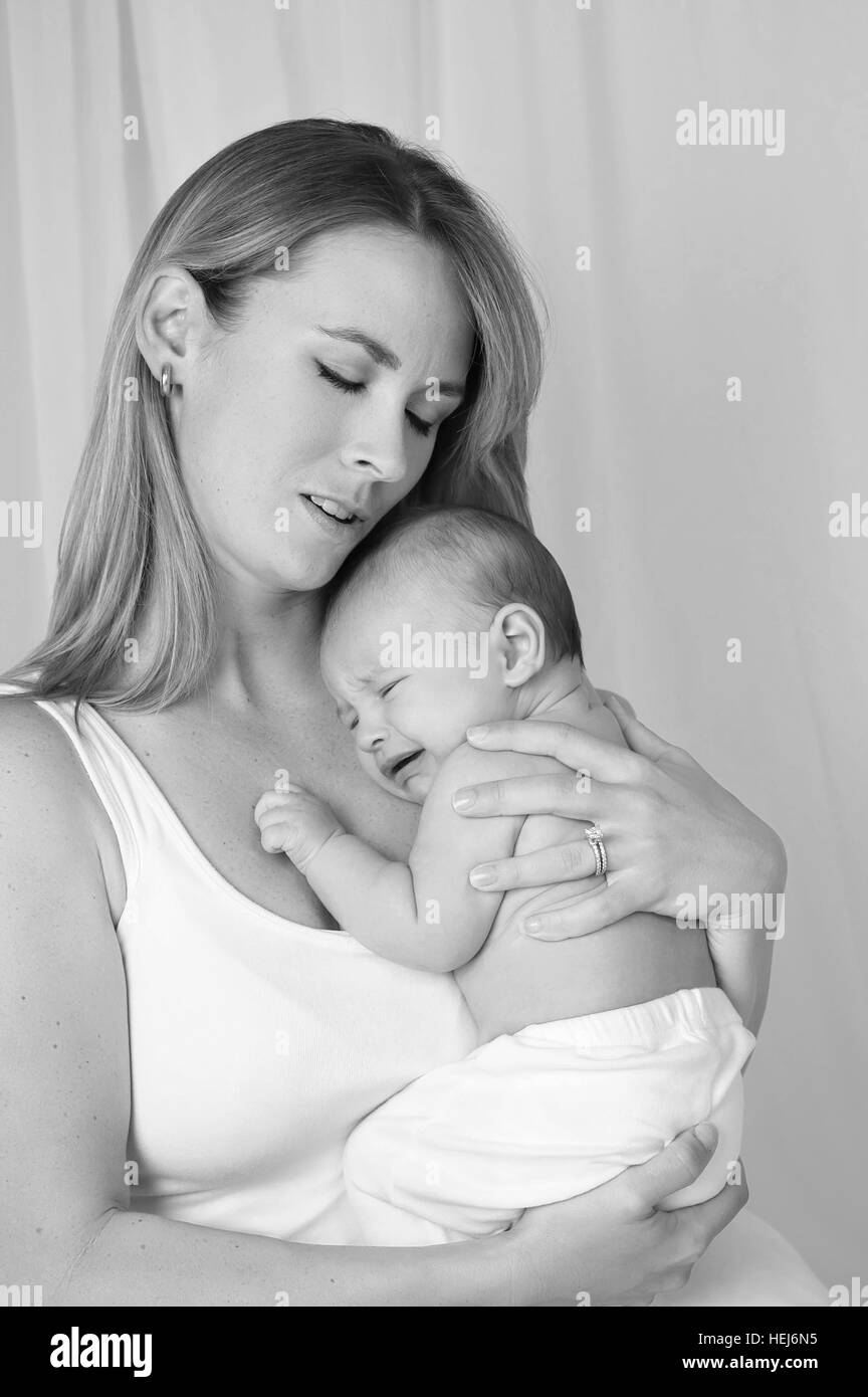 A black and white image of a mother comforting her crying baby boy. Stock Photo