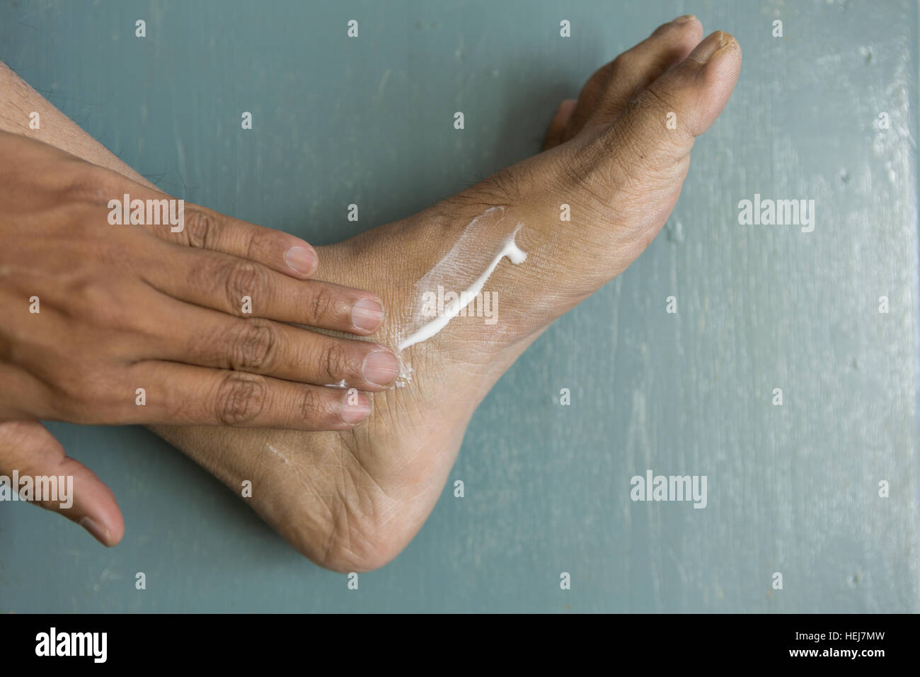 HYDERABAD, INDIA - DECEMBER 22,2016 Close-up of foot and hand of Asian male Adult of Indian origin applying lotion on dry skin Stock Photo