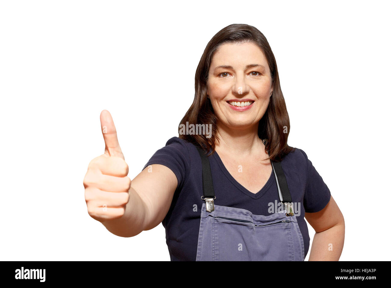 Middle aged saleswoman of a hardware shop wearing dungarees and showing the thumbs up sign, isolated on white, copy space, copyspace Stock Photo