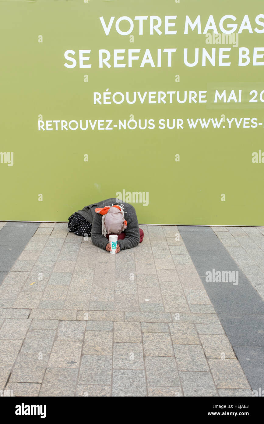 A homeless woman begging on the street in Paris outside a shop undergoing refurbishment. Stock Photo