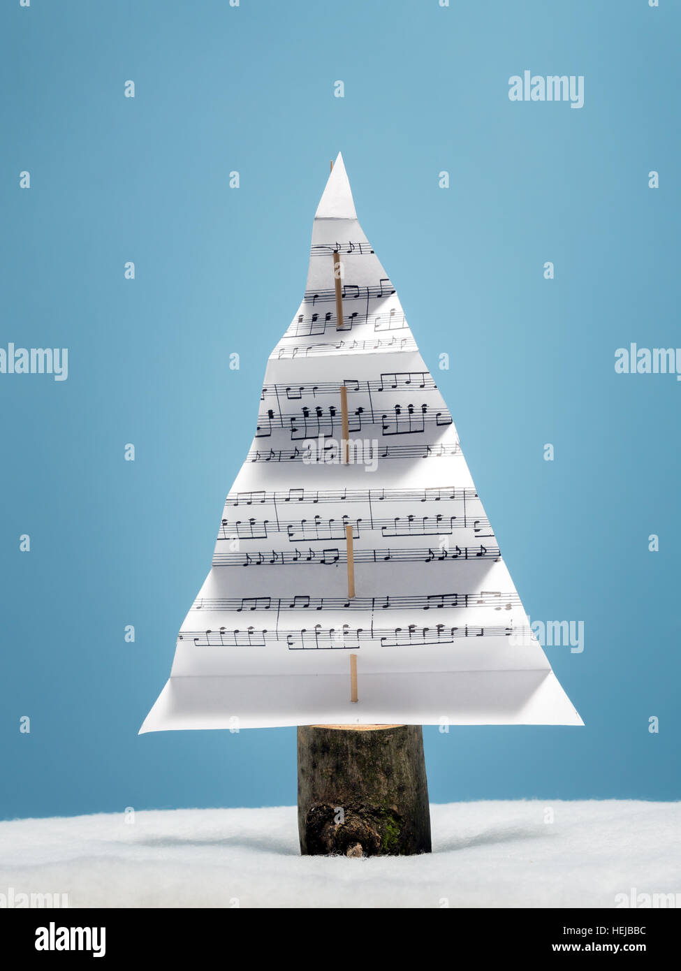 Paper christmas tree with christmas carol notes over light blue background Stock Photo