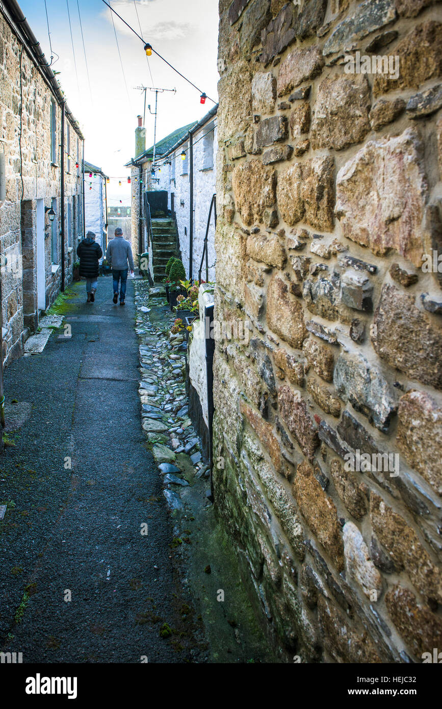 A couple walking down the quaint picturesque Duck Street in the historic village of Mousehole, Cornwall. Stock Photo