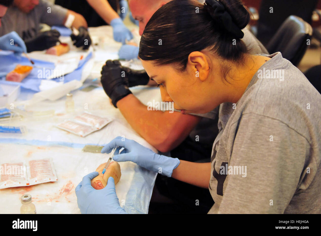 Spc. Denise Ismerio, a medic with Company B, Division Special Troops Battalion, 1st Armored Division and Rialto, Calif., native, injects a pig's foot with sterile water during a training exercise at the DSTB Aid Station on Camp Liberty, Iraq, July 11. The water was used in place of a local anesthetic. 1st Armored Division medics practice suturing on pig's feet 298241 Stock Photo